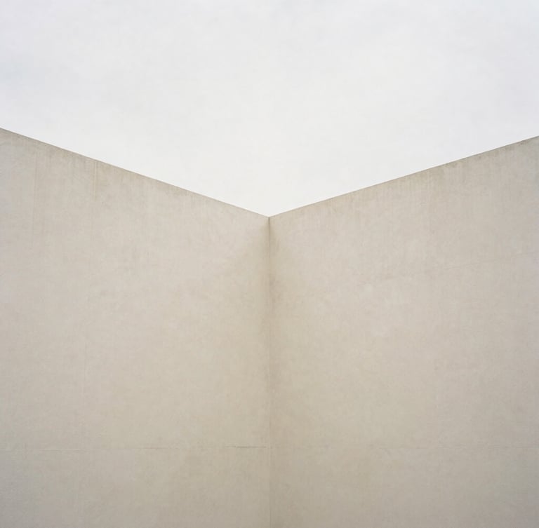 Minimalist architectural composition of intersecting concrete planes, soft overcast daylight, subtle shadows, cream and muted earth tones, 35mm
