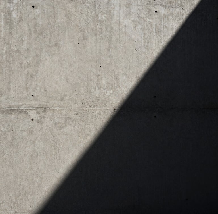 Extreme close-up of raw concrete corner with dramatic diagonal shadow, stark high-contrast natural daylight.