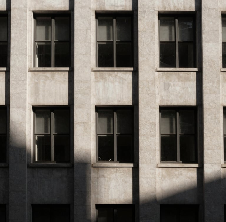 Stark minimalist architectural detail of a historic financial building facade, sharp directional window light casting deep geometric shadows, desaturated warm tones, high-contrast 35mm composition with generous negative space