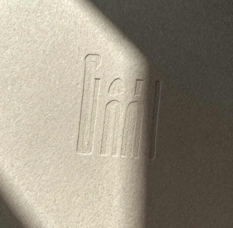 A macro detail of heavy cotton paper with deep letterpress ink impressions, sharp directional light, dramatic shadows, desaturated warm tones.