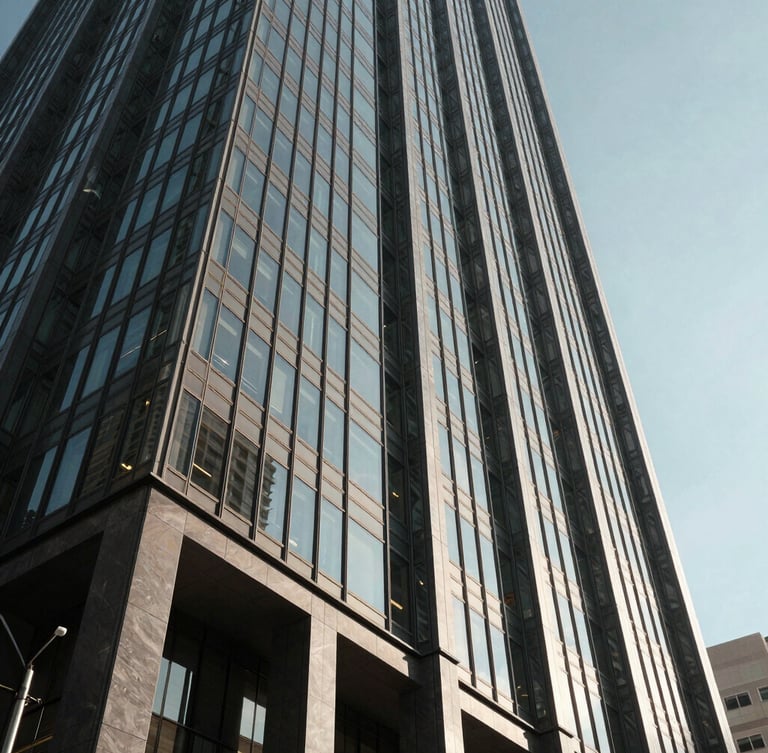 Low-angle architectural shot of a modern glass skyscraper in Houston, sharp shadows, dramatic afternoon sun cutting through steel structures, high-contrast.