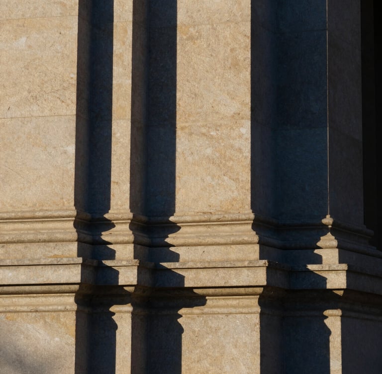 Abstract architectural detail of a structural stone column, crisp natural daylight with sharp shadows, deep navy and muted gold tones, 35mm