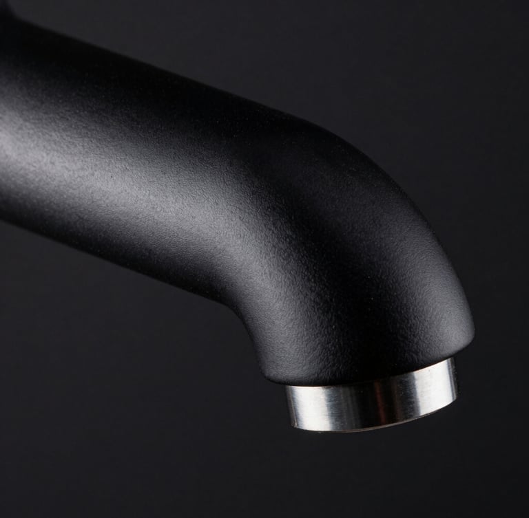 Extreme macro shot of a monolithic matte black faucet spout, high-contrast side-lighting catching the sharp metallic edge, dark background.