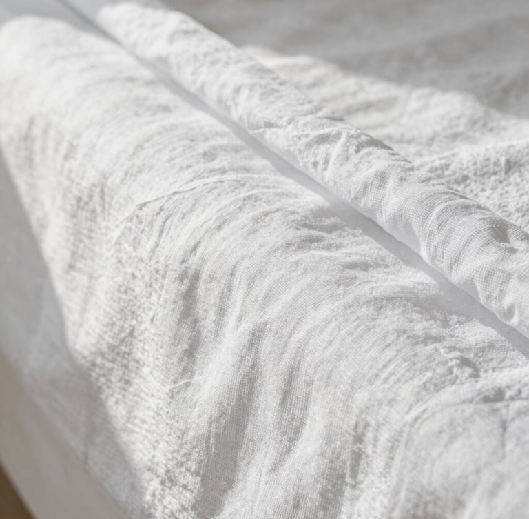 Macro shot of perfectly ironed white linen sheets, crisp textures with soft natural morning light, clean shadows, minimalist composition.