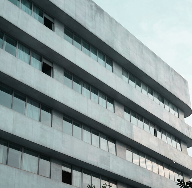 A sharp architectural close-up of a modern pharmaceutical research facility facade in Bangalore, desaturated teal and slate tones, cool diffused morning light.