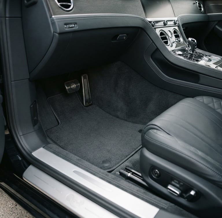 Wide panoramic luxury car interior footwell, dark grey tailored mat perfectly fitted, laser-cut edge detail visible, soft natural daylight, minimalist aesthetic, 35mm