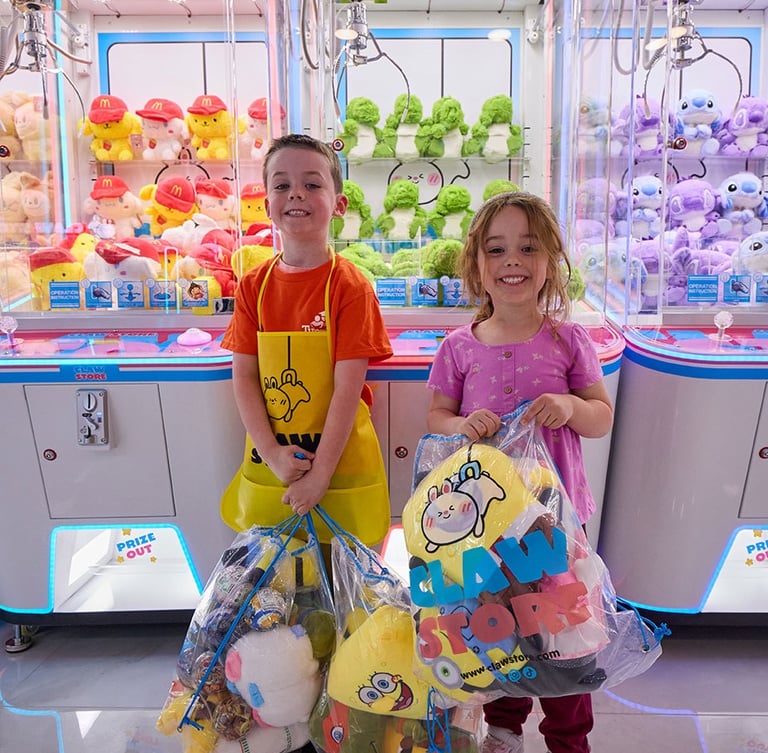 kids with plushies next to claw machines