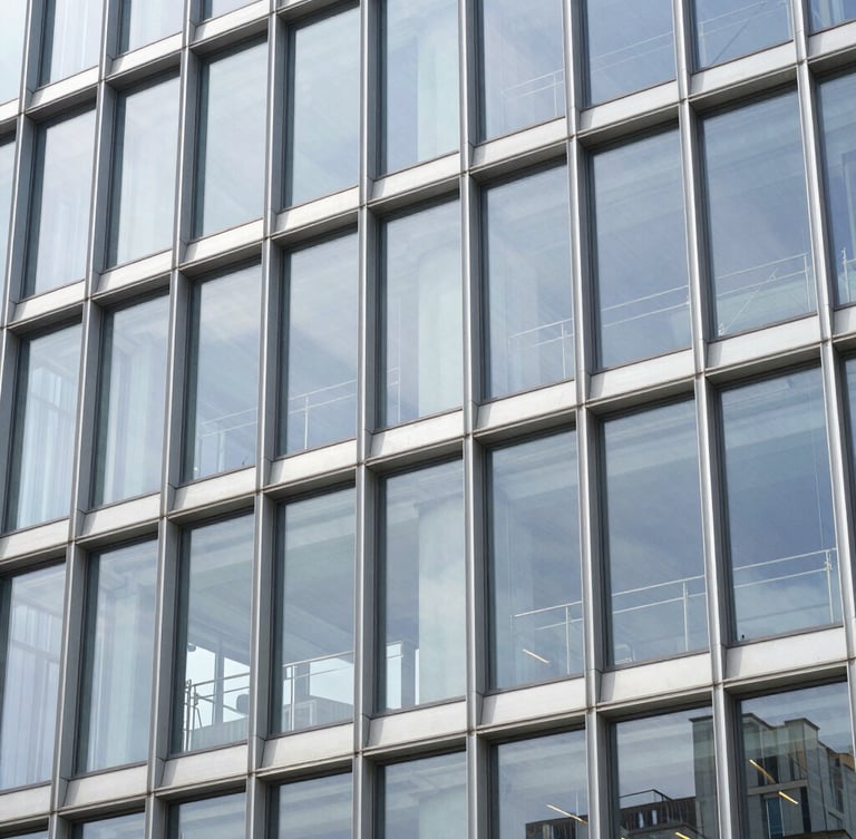A modern commercial glass facade with clean aluminum frames, bright daylight reflecting off the energy-efficient glass, professional finish.