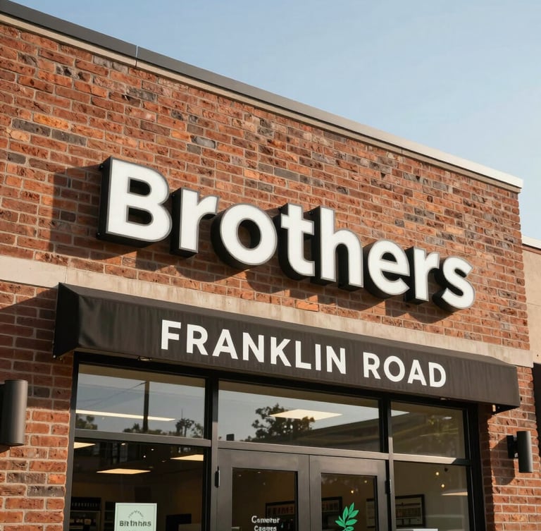 Bright daylight medium shot of the Brothers Cannabis storefront exterior on Franklin Road, professional clean signage, warm brick architecture, clear sky.