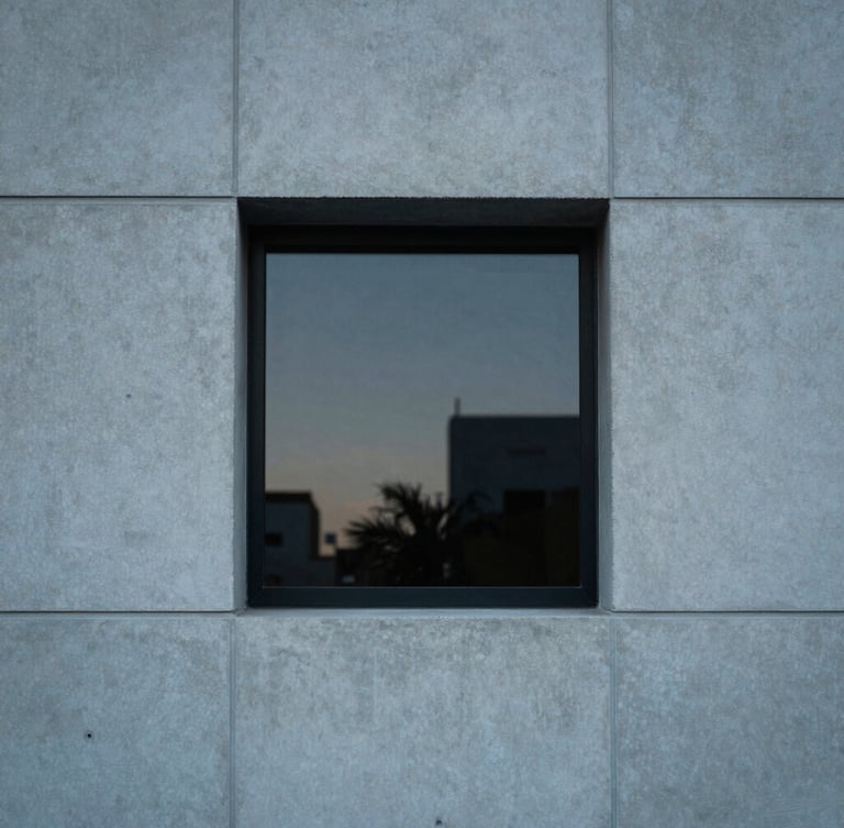Tight architectural crop of a minimalist concrete facade in Miami, soft diffused late-afternoon window light, muted blue and charcoal tones, 35mm