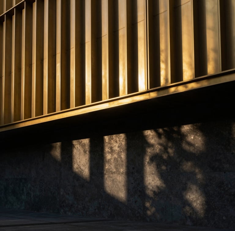 Dramatic architectural photography of a golden laser-cut metal facade during golden hour, sharp geometric shadows cast on a dark concrete wall, 35mm