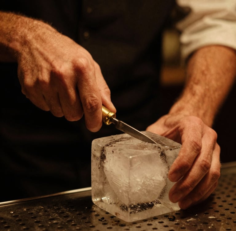 Close-up of a bartender carving a clear block of ice with a brass tool, warm low-key amber lighting, rich saturated tones, 35mm film