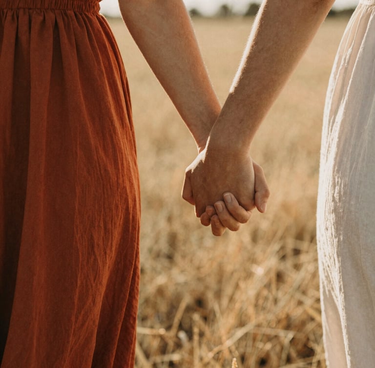 Intimate close-up of a couple holding hands, walking through a sunlit field, warm golden light, shallow depth of field, 35mm film grain, cinematic