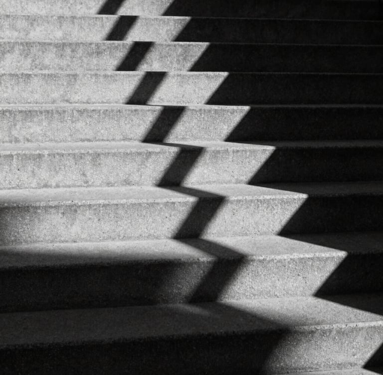 Stark black and white architectural shadows cast on concrete steps, high-contrast chiaroscuro, sharp focus, geometric lines, 35mm film
