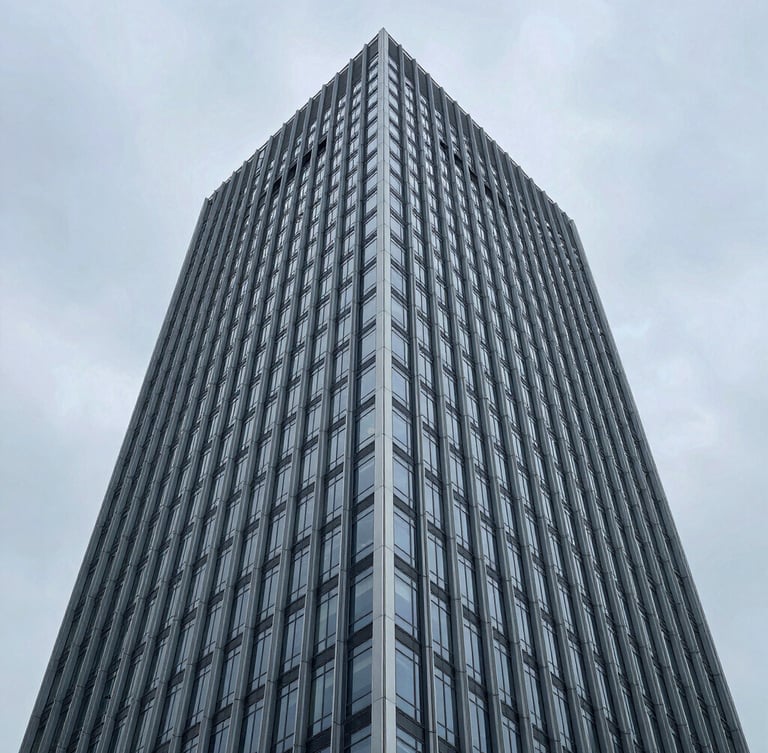 High-angle architectural detail of a modern steel and glass skyscraper facade against a cool overcast sky, clean geometric lines.