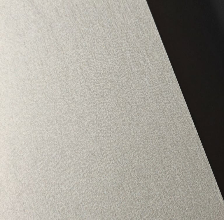 Extreme close-up of high-end textured heavy cotton paper with fine debossed lines, dramatic side-lighting, minimal editorial style, sharp focus