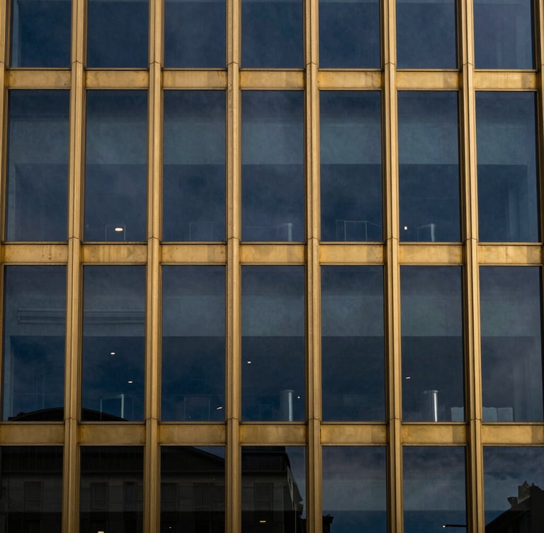Macro high-contrast architectural detail of a gold-trimmed glass facade reflecting deep twilight sky