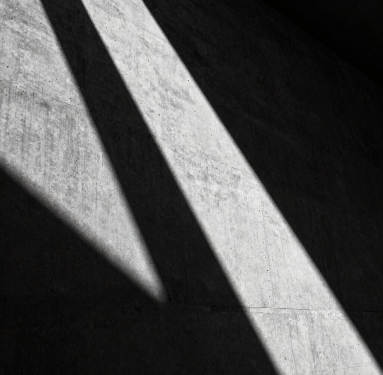 Extreme close-up of harsh low-angle sunlight grazing raw concrete, casting a deep diagonal shadow, 35mm architectural photography, high-contrast monochrome