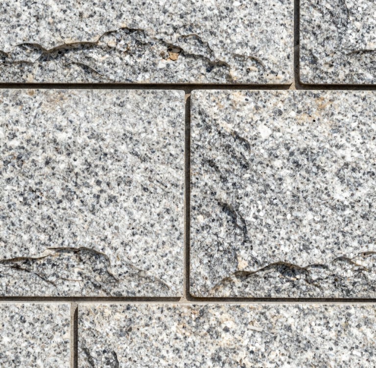 Close-up macro shot of perfectly aligned stone joints on a newly completed granite retaining wall, bright morning daylight, sharp focus.