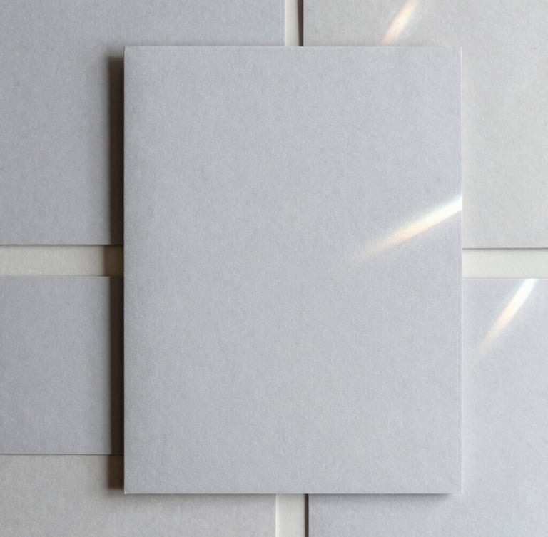 Overhead flat lay of a minimalist brand stationery suite, soft silver gray paper, delicate blind debossing, elegant