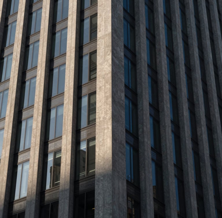 A sharp, high-contrast close-up of a modern concrete and steel skyscraper facade, dramatic architectural shadows, cool ambient twilight light.