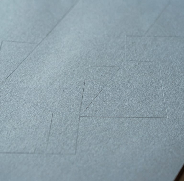 Extreme close-up of fine textured cotton paper with deep debossed geometric lines, soft daylight casting subtle shadows across the surface, minimalist editorial composition, 35mm.