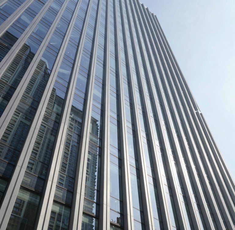 Wide-angle architectural shot of a modern vertical high-rise facade under crisp daylight, showcasing flawless structural glass joints and clean steel lines with sharp geometric shadows.