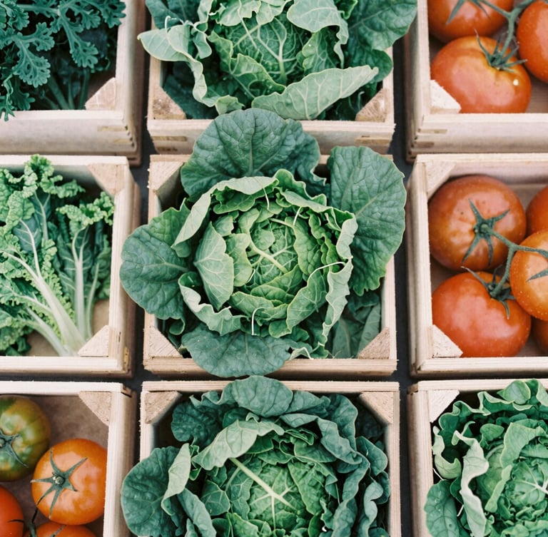 Overhead flat-lay of raw wooden crates overflowing with fresh seasonal leafy greens and heirloom tomatoes, soft overcast daylight, organic textures.