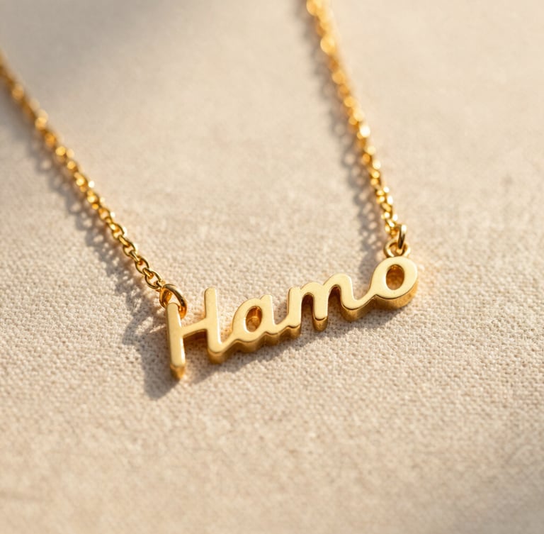 Macro shot of a custom gold nameplate necklace resting on raw linen texture under warm Pacific golden-hour sunlight