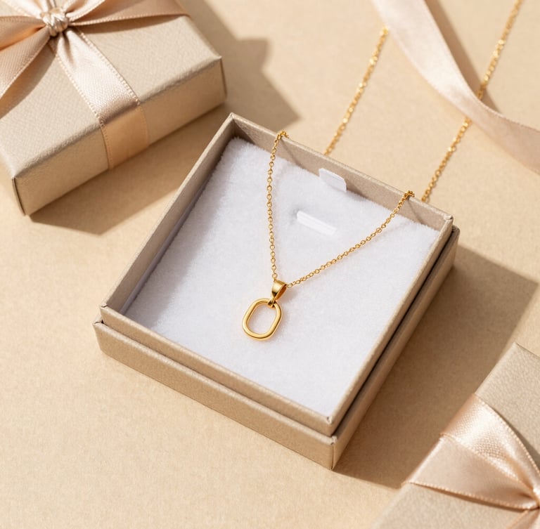 Overhead flat lay of elegant jewelry gift packaging on a soft sand-beige surface, featuring a gold-plated necklace nestled inside a premium custom box with delicate ribbon.
