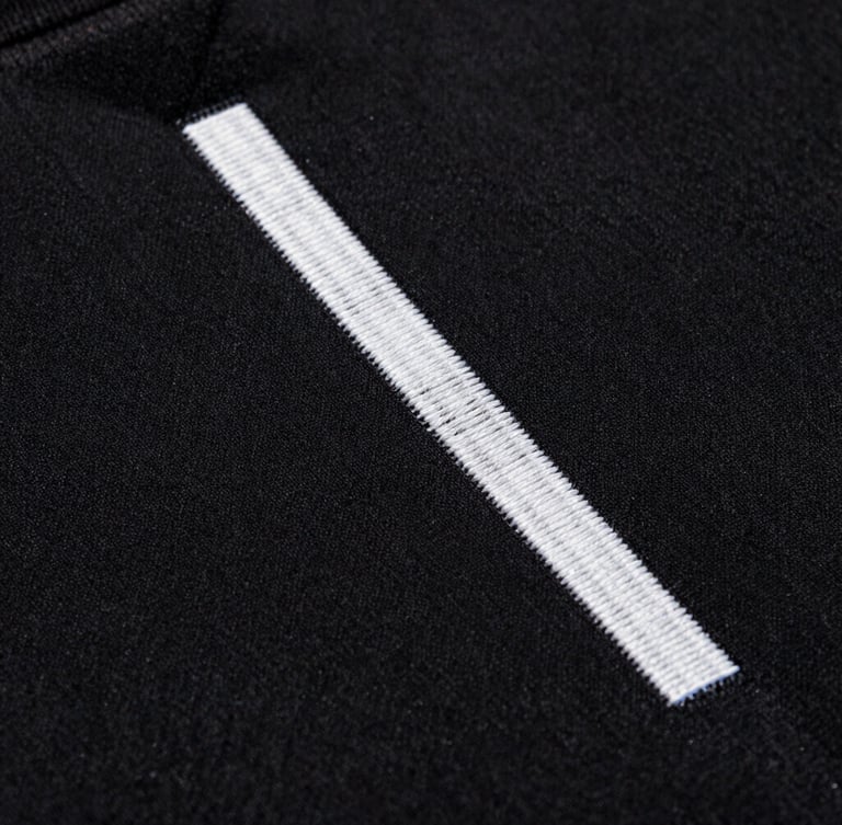 Macro extreme close-up of high-density embroidery on heavy black cotton fabric, sharp studio lighting, dramatic shadows, 35mm film grain