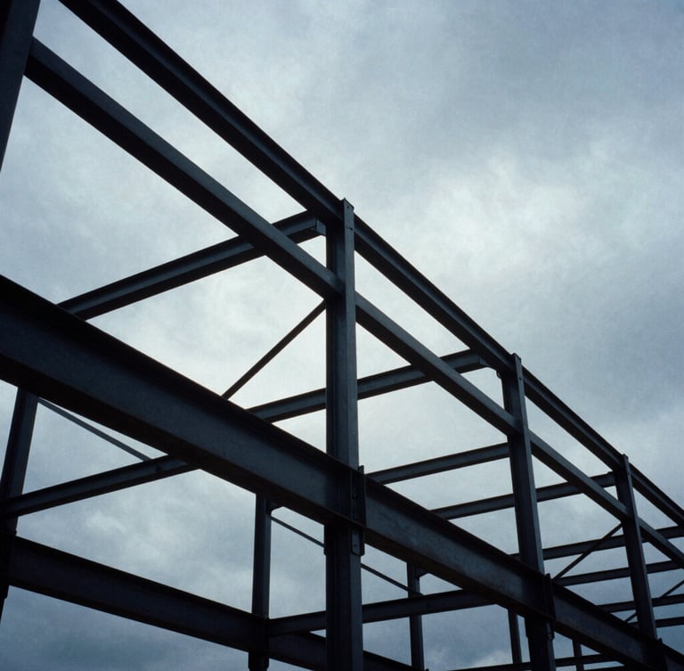 Low-angle heroic shot of massive structural steel frameworks against a dramatic overcast sky, cool industrial tones, 35mm film.