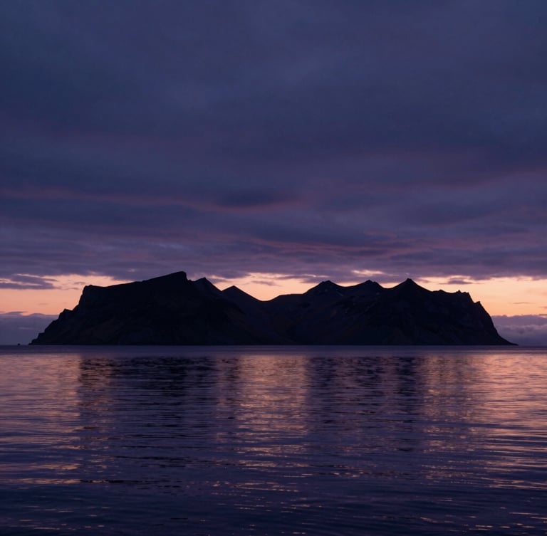 Horizonte minimalista al crepúsculo en Islandia, cielo oscuro con tonos índigo, siluetas de montañas lejanas y agua calma reflejando la última luz.