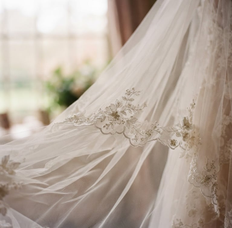 Close-up of a delicate bridal veil, sculpted tulle draped softly, catching diffused window light, shallow depth of field, romantic editorial photography