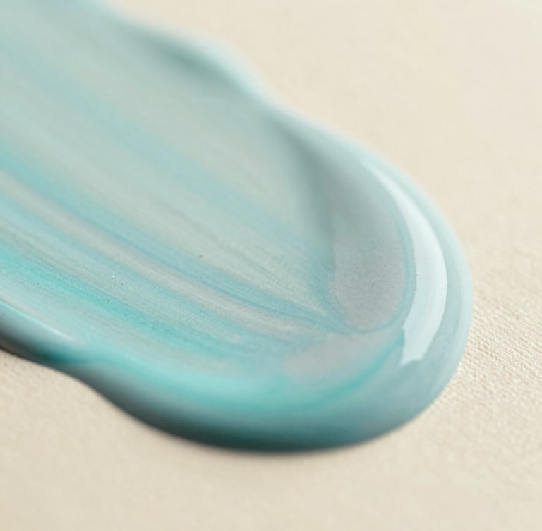 Macro close-up of soft cyan and mist gray fluid acrylic paint blending smoothly on a warm cream canvas, soft diffused daylight, shallow depth of field