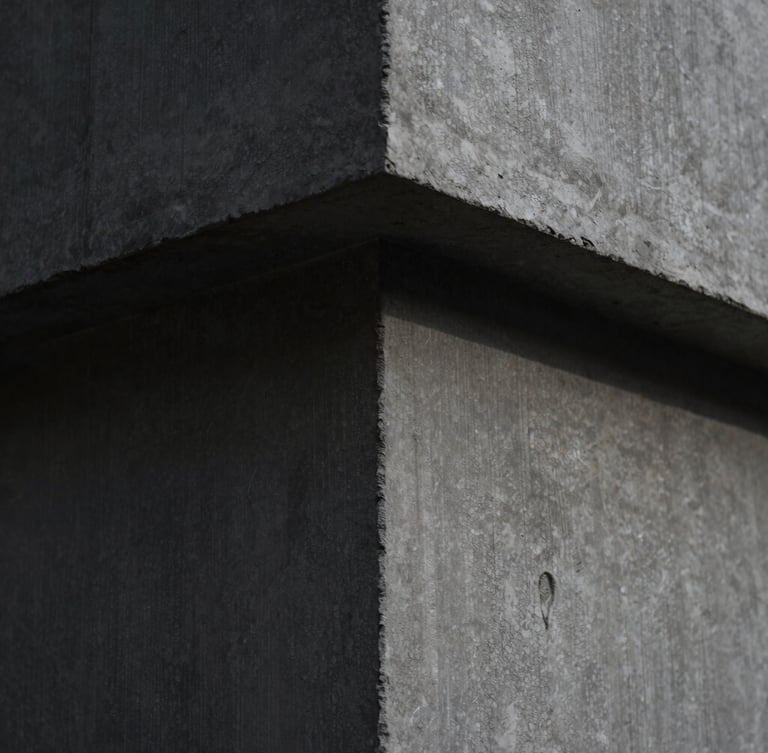 Extreme close-up of smooth, architectural raw concrete with subtle formwork lines, dramatic side-lighting casting deep shadows, highlighting the fine grain and monolithic texture, 35mm lens.