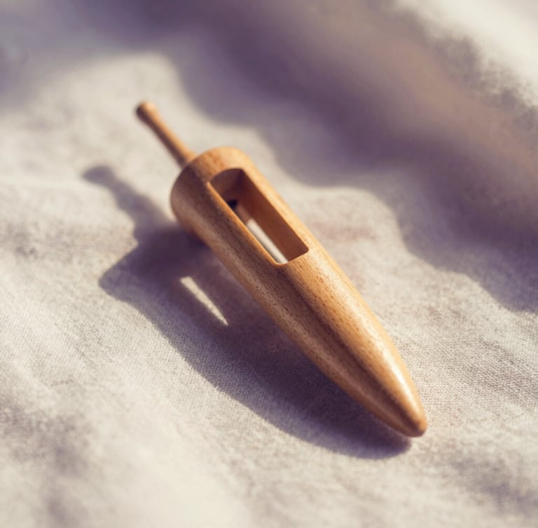 Macro shot of a wooden Hebrew pendulum held gently over clean linen, soft diffused morning light, warm cream and deep purple shadows