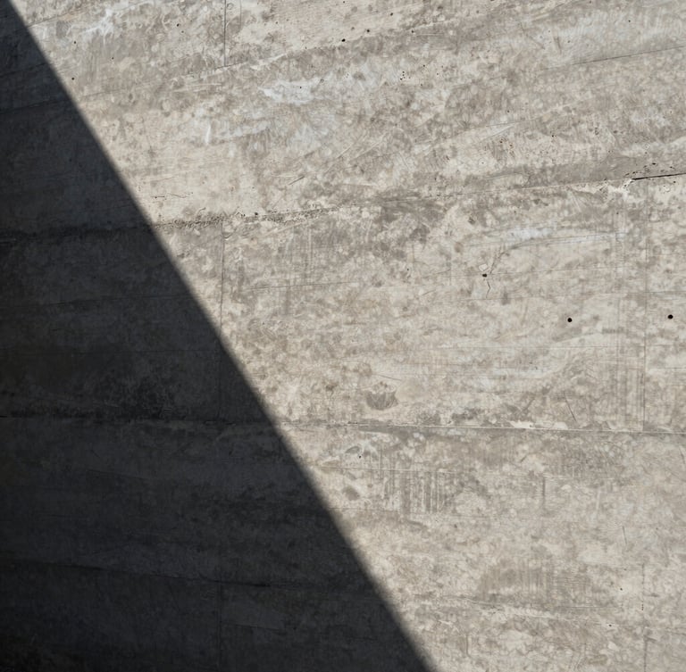 Extreme close-up of textured raw board-formed concrete wall, sharp sunlight casting deep geometric shadows across the grain, architectural detail.