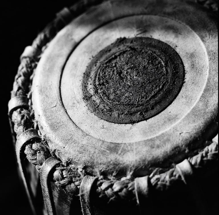 Extreme close-up macro shot of classical Indian Tabla leather head, dramatic side lighting casting deep shadows, high-contrast black and white, 35mm