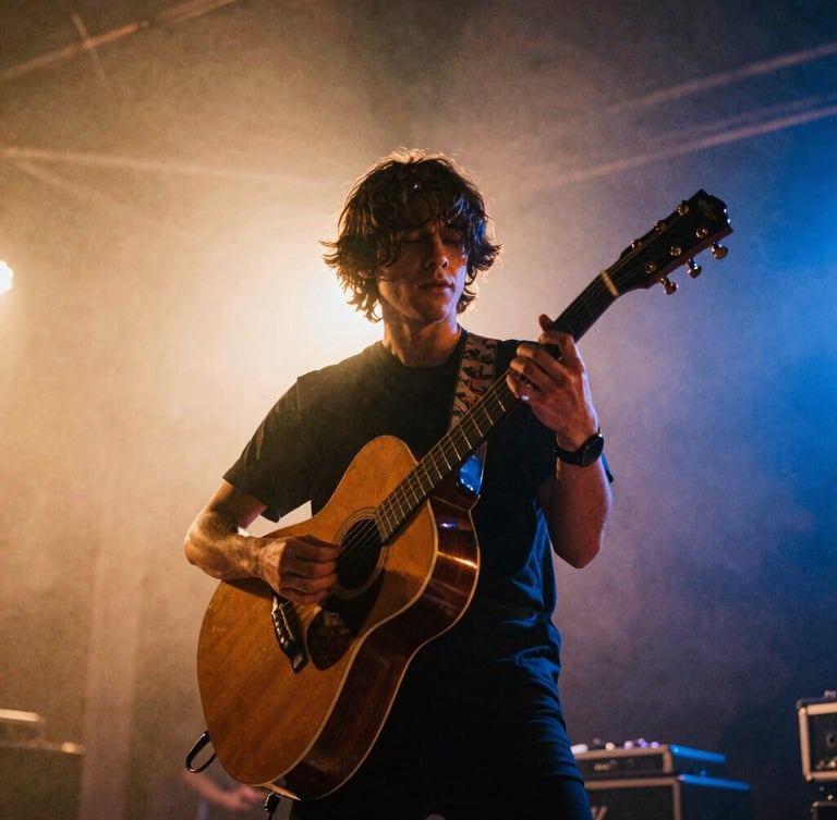 Low-angle dynamic shot of a musician playing an acoustic guitar on stage, warm amber backlighting, stage haze, 35mm film grain