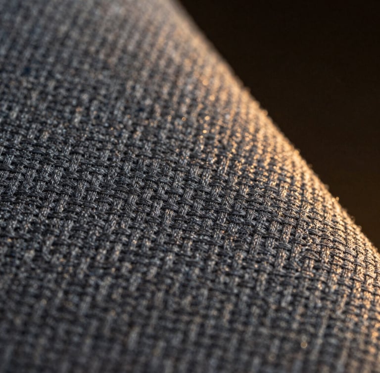 Macro close-up of structured grey uniform twill fabric, highlighting the diagonal weave pattern, dramatic side lighting, dark moody background