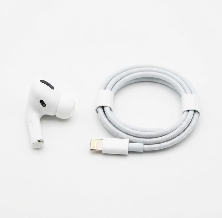 Bright, high-key studio shot of a modern wireless earbud and a charging cable arranged neatly on a white backdrop, sharp focus, clean shadows.
