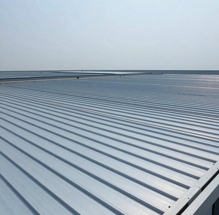 Wide-angle technical shot of a massive industrial roof installation, showing continuous zip-roofing profiles stretching across the structure under crisp overcast daylight, cool metallic blue tones, 35mm