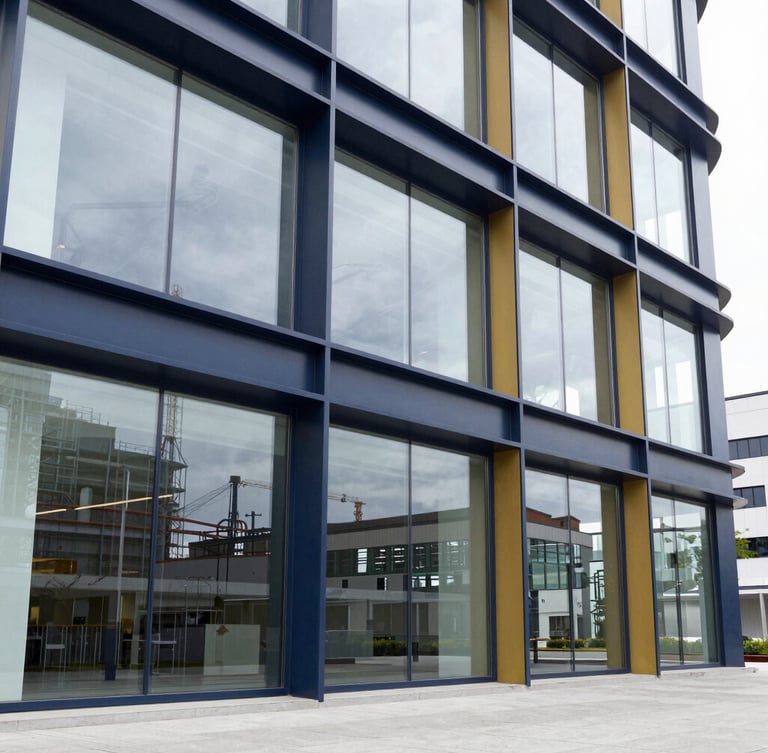 A bright corporate office with large glass windows showing industrial architecture in the background, sharp natural daylight, premium editorial style