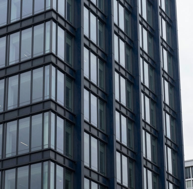 Architectural detail of a modern financial district building with structural glass and deep navy steel columns, cool overcast daylight.