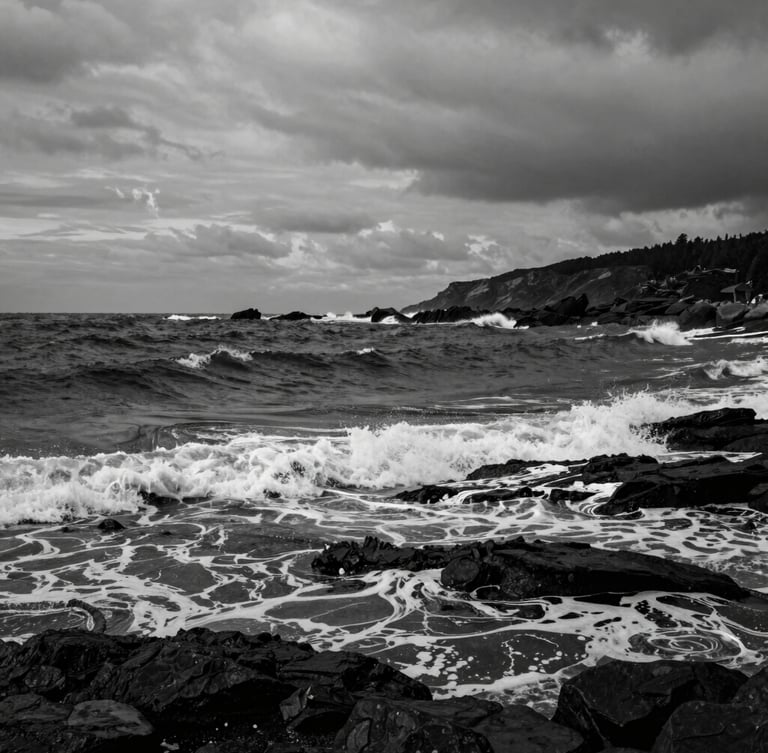 Dramatic black and white photograph of the rugged Ordu coastline, dark moody sea with crashing waves, overcast coastal daylight, high contrast, fine art photography style