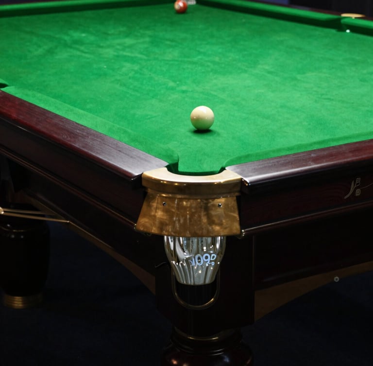 Moody editorial photography of a pristine snooker table corner, polished brass pocket, deep forest green felt under dramatic overhead spotlight, 35mm