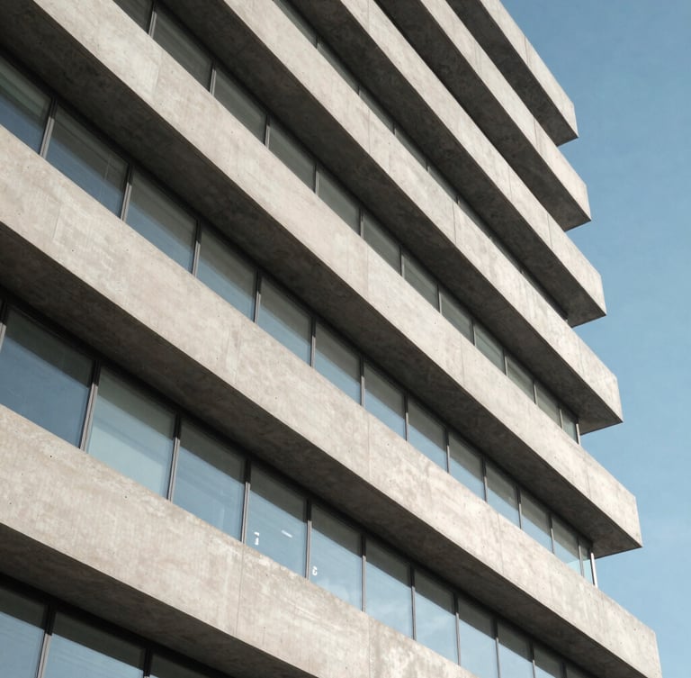 A high-altitude architectural abstract of a modern data center exterior, clean concrete lines and clinical daylight, orthogonal angle.
