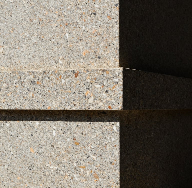 Extreme close-up of hand-carved local stone joints on a monolithic granite wall, harsh high-contrast tropical sunlight casting deep shadows, minimalist architectural photography, 35mm lens