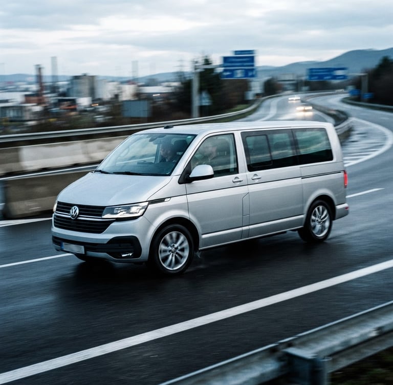 Dynamic low-angle tracking shot of a modern silver express minivan speeding on a European highway in cool morning daylight, motion blur, sharp high-contrast industrial tones, 35mm